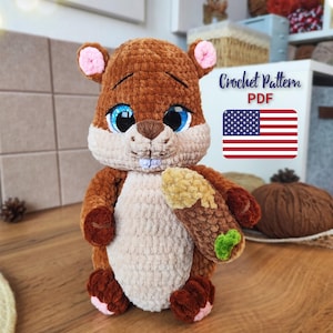 May include: A handmade crochet squirrel plushie in shades of brown, beige, and pink, holding a log-shaped item. The squirrel has large blue eyes and a sweet expression. The image includes text that says "Crochet Pattern PDF" and the American flag.