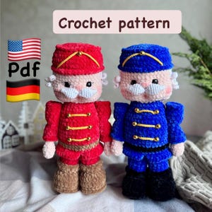 Puede incluir: Dos muñecos cascanueces de ganchillo, uno rojo y otro azul, con bigotes y sombreros blancos. Los muñecos tienen detalles de botones dorados y están etiquetados como "Crochet pattern" y "Pdf".