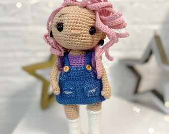 May include: A crocheted doll with pink hair, a purple and blue dress, and white socks and red shoes.