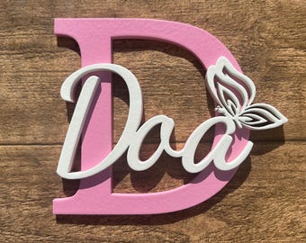 Op de afbeelding: Roze houten letter D met een witte vlinder en het woord "Papa" in witte letters.
