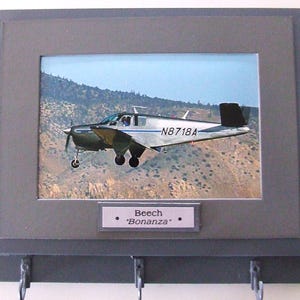 Wall Mounted Keychain Rack with a 4&quot;X6&quot; print of a Beechcraft Bonanza civilian aircraft.  Mounting screws are included.