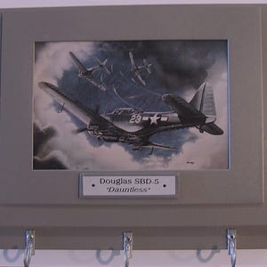An der Wand befestigte Schlüsselleiste mit einem Druck eines Douglas &quot;&quot;Dauntless&quot;&quot; Tauchbombers, der sich zum Schlag vorbereitet.&quot;