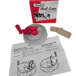 May include: A gray and red Imra wool cutter for Smyrna work with its original red and white box, two small rectangular blades, and an instruction sheet featuring diagrams and text detailing thread lengths of 2 3/16 inches to 2 3/4 inches.