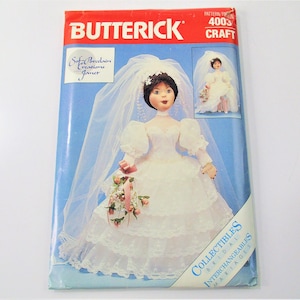 May include: A vintage Butterick pattern for a collectible bridal doll. The pattern number is 4003 and is labeled "Craft". The doll is wearing a white wedding dress with lace trim and a veil. The doll is holding a bouquet of flowers.