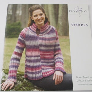 May include: A woman wearing a striped sweater in shades of pink, purple, and gray. The sweater has a V-neck and is knitted. The image is from a knitting pattern book titled "Stripes" by Nashua Handknits. The book is part of the North American Lifestyle Series, Fall and Winter 2006.