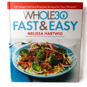 May include: The Whole30 Fast & Easy cookbook cover features a colorful image of a stir-fry dish with broccoli, red onion, and meat in a blue bowl. The title "The Whole30 Fast & Easy" is in large, bold letters with the author's name, Melissa Hartwig, below it.
