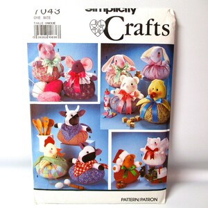 May include: A Simplicity Crafts sewing pattern with a blue background and illustrations of 9 different stuffed animal toys. The pattern number is 7043 and the title is "Crafts".
