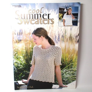 May include: A crochet pattern book titled "Cool Summer Sweaters" by Kathryn A. Clark. The cover features a woman wearing a beige crochet top with short sleeves.