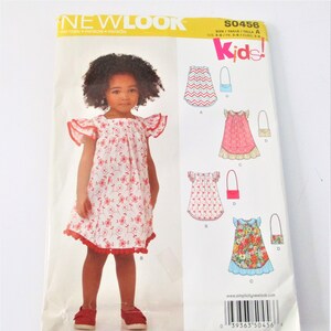 May include: A sewing pattern for a child's dress and matching bag. The pattern is for sizes 3-8. The pattern includes a floral print dress, a chevron print dress, and a floral print dress with a ruffled hem. The pattern also includes a small bag with a strap.