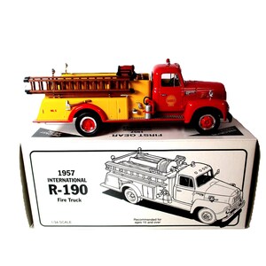 May include: A red and yellow 1957 International R-190 fire truck model, 1/34 scale, with a ladder and Shell logo. The model is on a white box with the truck's image and text.