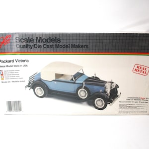 May include: A blue and black Packard Victoria model car kit with over 75 realistic pieces. The box features a photo of the assembled model car, with a white convertible top. The box also includes the text "Scale Models Quality Die Cast Model Makers" and "Real Metal".