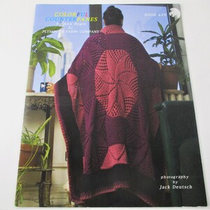 May include: A book titled "Colorful Counterpanes" by Ann Regis for Plymouth Yarn Company. The book cover features a woman wearing a crocheted blanket in shades of pink and purple. The book is number 639 in a series and the photography is by Jack Deutsch.