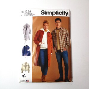 May include: Simplicity sewing pattern R11228 for a long-sleeved shirt and a jacket. The pattern includes instructions for sizes XS-XL. The image shows two models wearing the finished garments. The woman is wearing a rust-colored jacket and the man is wearing a plaid shirt.