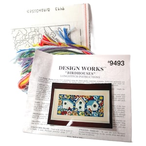May include: A cross-stitch kit featuring a colorful design of three birdhouses with flowers and birds. The kit includes a printed canvas, embroidery floss, and instructions. The kit is titled "Design Works™ "Birdhouses" Longstitch Instructions" and has the number #9493.
