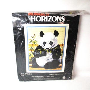 May include: A Monarch Horizons needlepoint kit featuring a black and white panda bear sitting in a bamboo forest. The kit is titled "The Panda" and includes instructions for completing the design.