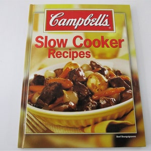 May include: A yellow cookbook with the title "Campbell's Slow Cooker Recipes" in red text. The cover features a photo of a bowl of beef bourguignon.