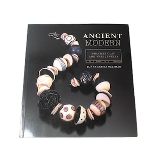 May include: A book titled "Ancient Modern: Polymer Clay and Wire Jewelry" by Ronna Sarvas Weltman. The cover features a colorful necklace made of polymer clay beads.