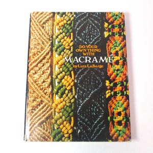 May include: A book titled "Do Your Own Thing With Macramé" by Lura LaBarge. The cover features various macramé patterns in shades of brown, green, orange, and black. The book is rectangular and appears to be in good condition.