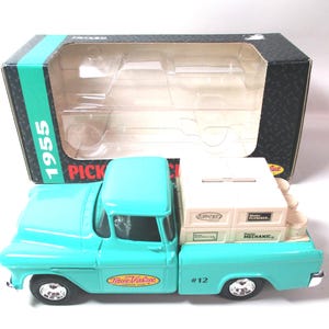 May include: A turquoise 1955 pickup truck model with the True Value logo on the door and #12 on the side. The truck bed carries four beige crates labeled Master Plumber, Master Electrician, and Master Mechanic. It includes a black and teal box.