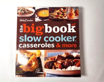 May include: A cookbook titled "The Big Book of Slow Cooker, Casseroles & More" by Betty Crocker. The cover features images of various cooked dishes, including soups, casseroles, and meat dishes. The book is set against a white background.