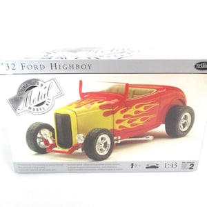 May include: A model kit box for a 1:43 scale '32 Ford Highboy. The box features a red and yellow model car with flames on the side. The box is labeled 'Metal Body Model Kit' and 'Testors'.