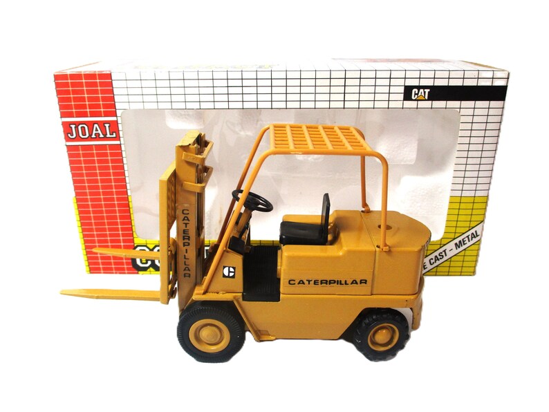 Może przedstawiać: Ż&oacute;łta zabawka w&oacute;zka widłowego Caterpillar z odlewanego metalu. W&oacute;zek widłowy ma czarne opony, czarne siedzenie i kierownicę. Pudełko ma logo JOAL i CAT.