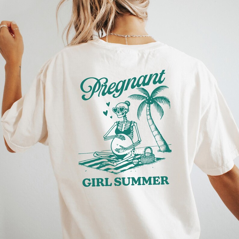 May include: White t-shirt featuring a green graphic of a skeleton wearing sunglasses and a bikini, sitting on a beach with a palm tree and the text "Pregnant Girl Summer".