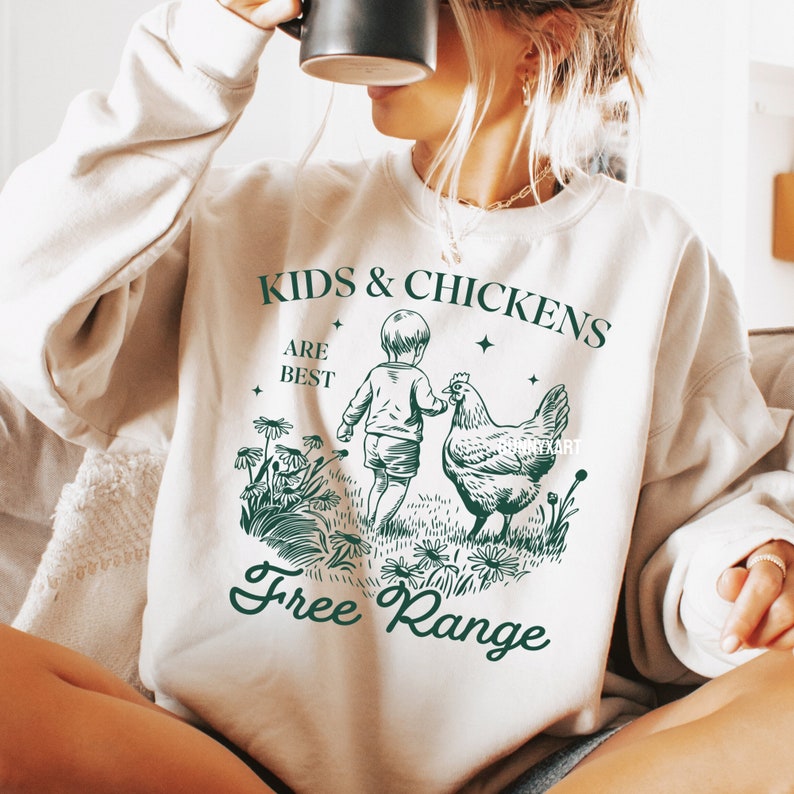 May include: A white sweatshirt with a green graphic design that says "Kids & Chickens Are Best Free Range". The graphic features a child holding a chicken's wing.