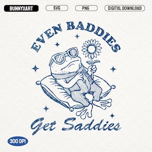 May include: A blue and white illustration of a frog wearing sunglasses and a striped shirt, holding a flower. The frog is sitting on a pillow with the text "Even Baddies Get Saddies" around it.