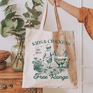 May include: A white canvas tote bag with a green design that says "Kids & Chickens Are Best Free Range". The design features a child holding a chicken's wing.