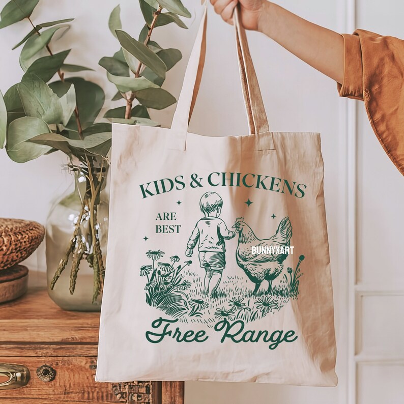 May include: A white canvas tote bag with a green design that says "Kids & Chickens Are Best Free Range". The design features a child holding a chicken's wing.