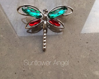 Colourful dragonfly brooch, with sparkling crystals in red and green, on a silver base.