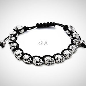 Könnte beinhalten: Ein Armband aus schwarzem Band mit silbernen Totenkopfperlen.