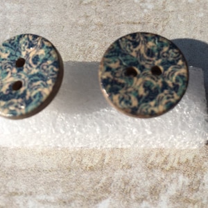 May include: Two ceramic buttons with a blue and white swirl pattern. The buttons have two holes each.
