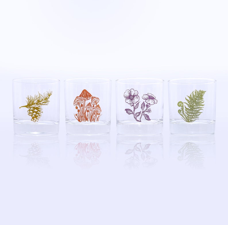 K&ouml;nnte beinhalten: Vier klare Glasbecher mit verschiedenen Naturmotiven. Die Becher zeigen eine Kiefernzapfen, Pilze, Blumen und einen Farn.