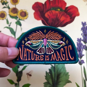 May include: A blue and green embroidered patch featuring a moth and the text "Nature is Magic".