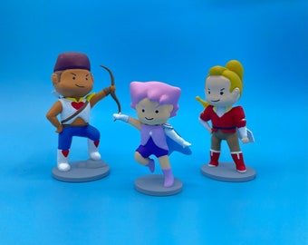 May include: Three hand-painted figurines of characters from a cartoon. The figurine on the left is a brown-skinned male character with a red heart on his chest, wearing a blue and red outfit. The figurine in the middle is a pink-skinned female character with a blue and purple outfit. The figurine on the right is a yellow-skinned male character with a red and yellow outfit.