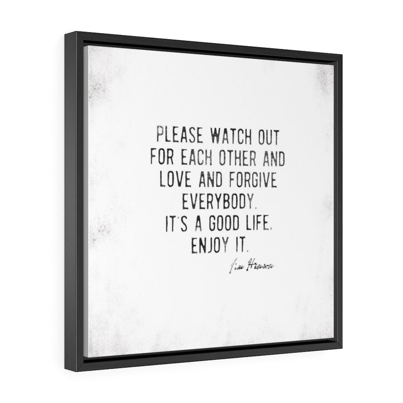 Op de afbeelding: Vierkante ingelijste wandkunst met een zwart frame. Het kunstwerk heeft een witte achtergrond met zwarte tekst die luidt: "PLEASE WATCH OUT FOR EACH OTHER AND LOVE AND FORGIVE EVERYBODY. IT'S A GOOD LIFE. ENJOY IT." Handtekening onderaan.