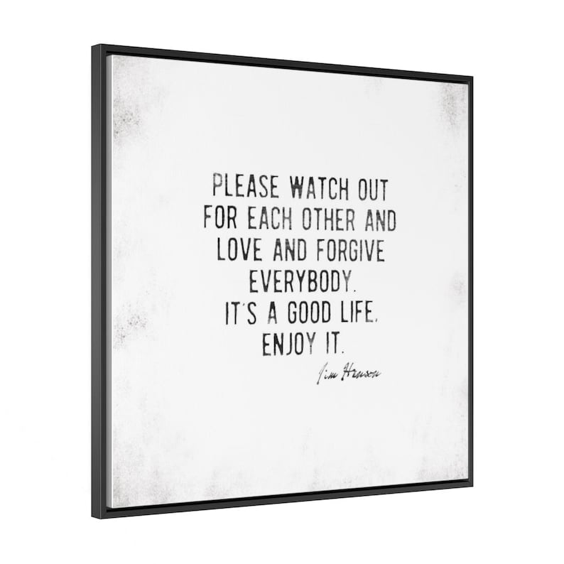 Op de afbeelding: Een ingelijste wandkunstprint met een zwart frame. Het kunstwerk heeft een witte achtergrond met zwarte tekst die luidt: "PLEASE WATCH OUT FOR EACH OTHER AND LOVE AND FORGIVE EVERYBODY. IT'S A GOOD LIFE. ENJOY IT." Handtekening onderaan.
