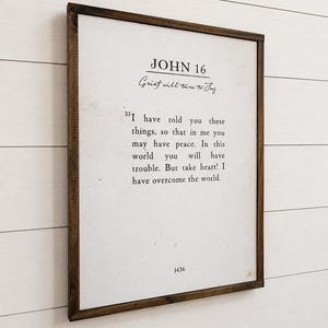 Puede incluir: Un marco de madera oscura que contiene una impresi&oacute;n con el texto "JOHN 16" y una cita sobre el dolor. El fondo es blanco con texto negro. El marco rectangular est&aacute; colgado en una pared blanca.