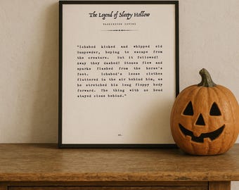 May include: A framed print of "The Legend of Sleepy Hollow" text sits on a wooden table next to a carved pumpkin. The pumpkin is orange with a carved face. The print has black text on a white background.