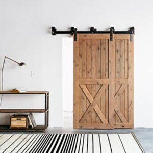 May include: A double barn door with a rustic wood finish and an X-shaped design. The door is mounted on a black metal track system.
