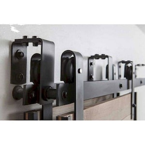 May include: Black metal sliding door hardware with a wooden door panel. The hardware includes a track, rollers, and brackets.