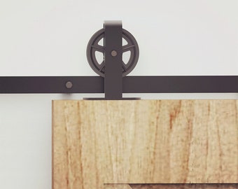 May include: A black metal sliding door track with a single black metal roller. The track is mounted to a light wood door.