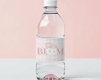 May include: Clear plastic water bottle with a white cap. The bottle has a label with the words "Sip & Bloom" in pink script and a daisy graphic, set against a pink and white gingham pattern.