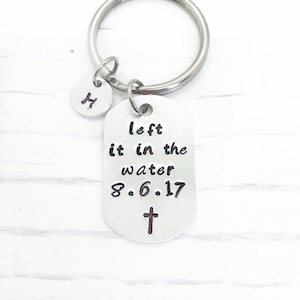 May include: Silver keychain with a tag that reads "left it in the water 8.6.17" with a small cross below the date. A small silver charm with the letter "H" is attached to the keychain.
