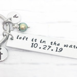 May include: Silver keychain with a cross charm, a pearl bead, and a rectangular tag that reads "left it in the water 10.27.19".