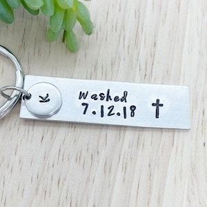 May include: Silver keychain with a small charm and a rectangular tag. The tag says "Washed 7.12.18" and has a cross symbol.
