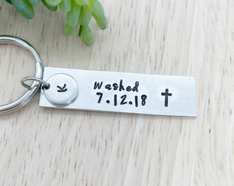 May include: Silver keyring with a small charm and a rectangular tag. The tag says "Washed 7.12.18" and has a cross symbol.
