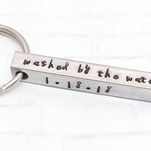 May include: Silver keychain with a rectangular charm engraved with the text "washed by the water 1-18-18".